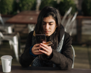 a person sits at a table holding a credit card and reading info on a smart phone
