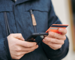 a man holds a credit card and a smart phone