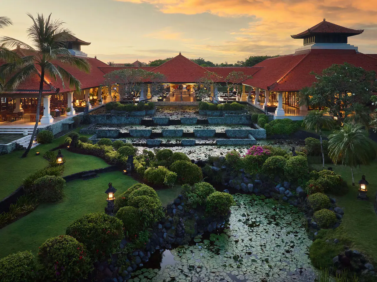 A picture of the lobby pools at the Grand Hyatt Bali showing bushes, trees, and multiple blue pools with buildings in the background. A stay here could help you earn Hyatt Milestone Rewards.