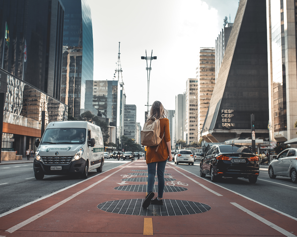 a woman seen from behind while walking down the pedestrian area in the middle of a busy avenue