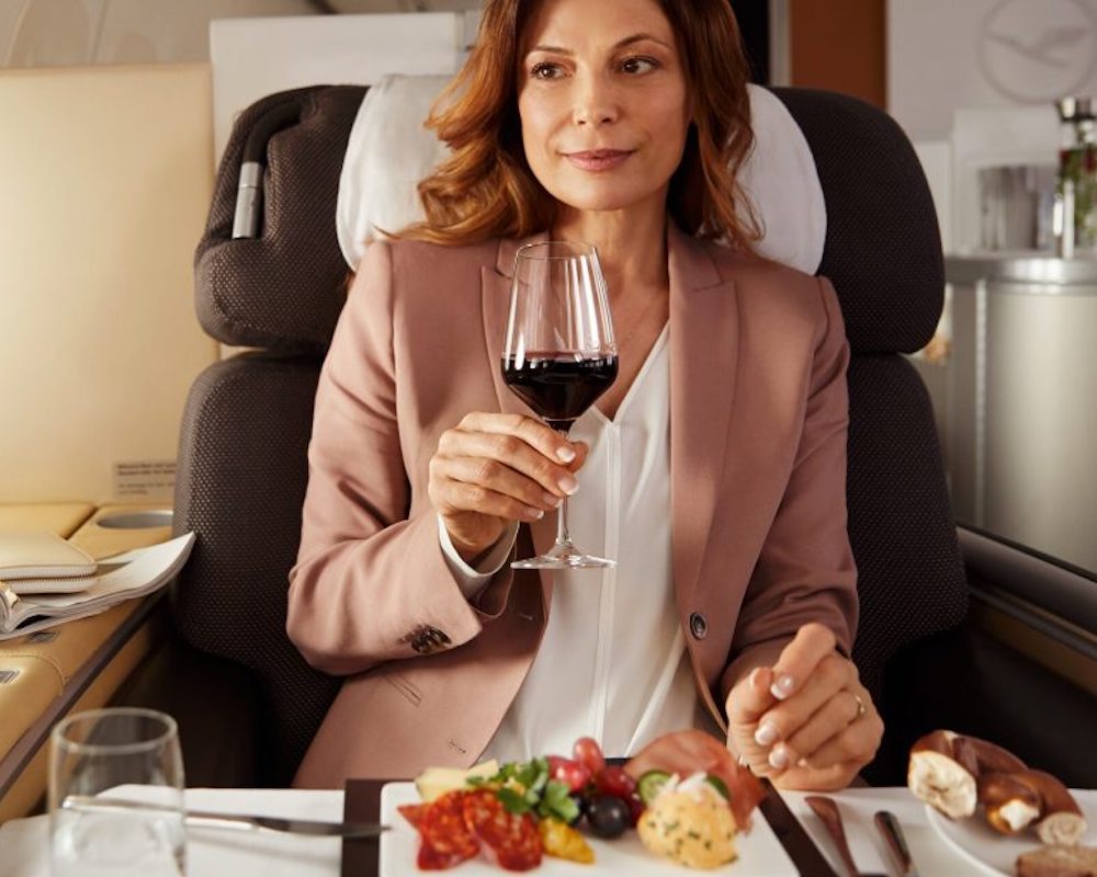 A passenger drinks wine in Lufthansa first class