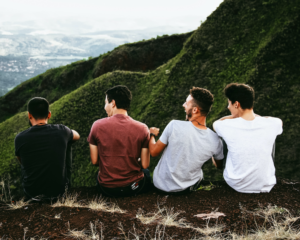 friends laugh together on a hilltop overlooking a city