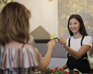 a woman pays with a credit card at a hotel reception desk