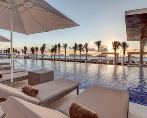 Sunset behind lounge chairs at the pool at the Royalton CHIC Cancun, an all-inclusive property from Marriott Bonvoy