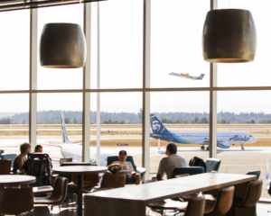 an Alaska Airlines plane is visible through the windows of an airport lounge
