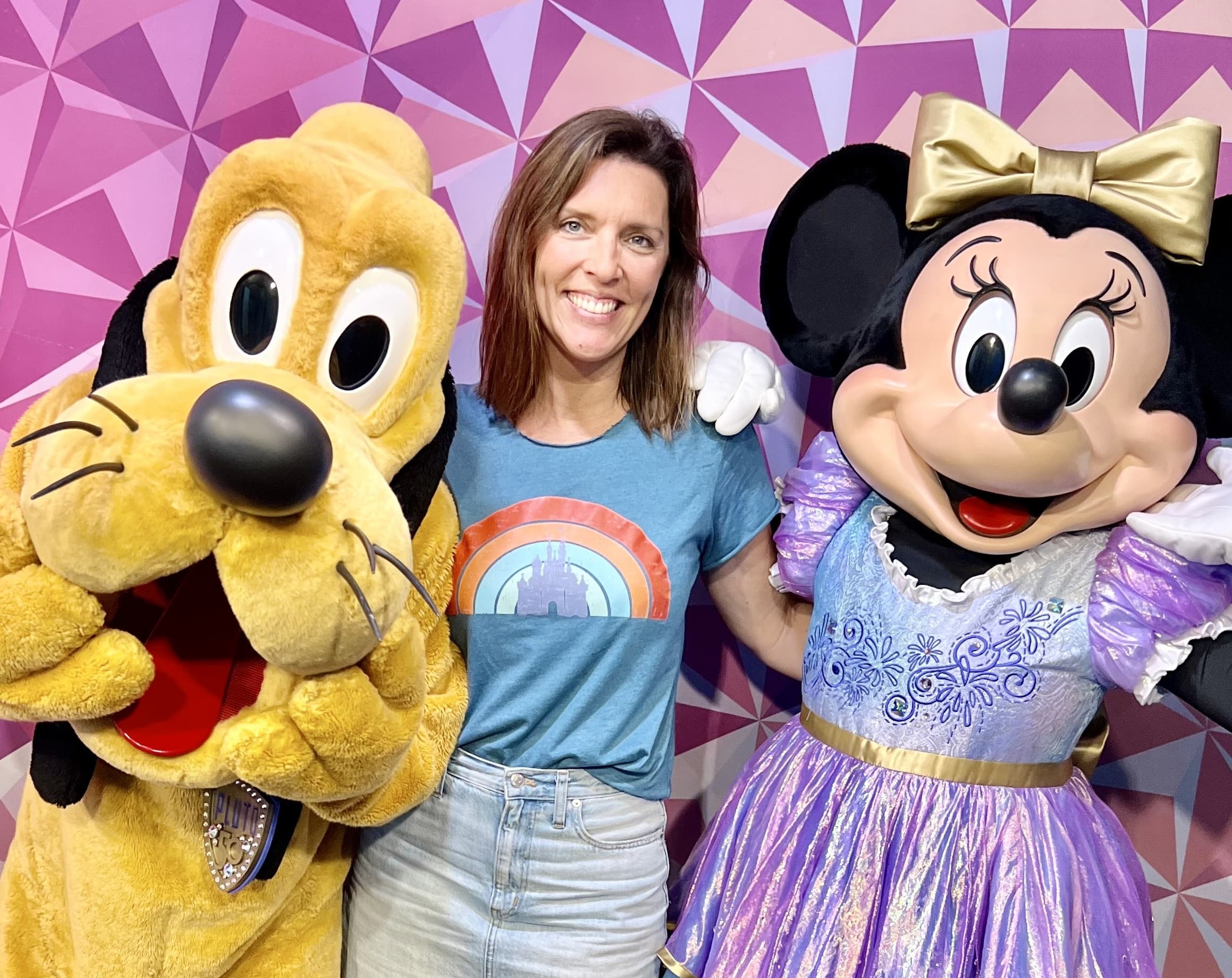 a woman poses with Minnie and Pluto at Disney World