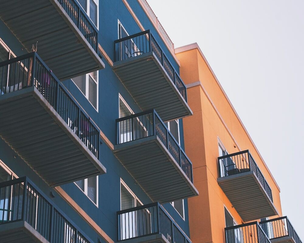 Siding of a blue and orange apartment building with extended balconies.