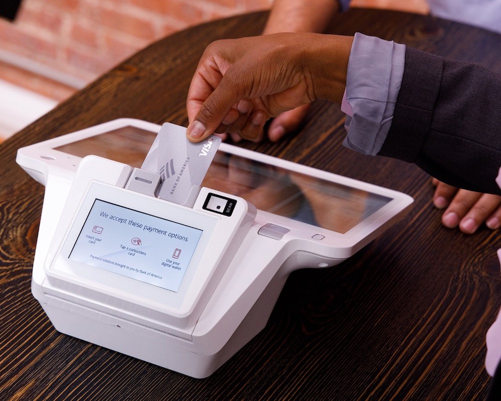 a hand inserts a BankAmericard credit card into a payment terminal