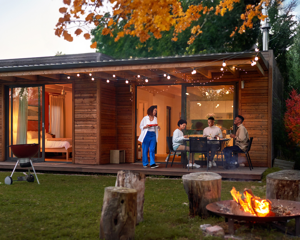 a family prepares for a BBQ dinner outside a home in the woods