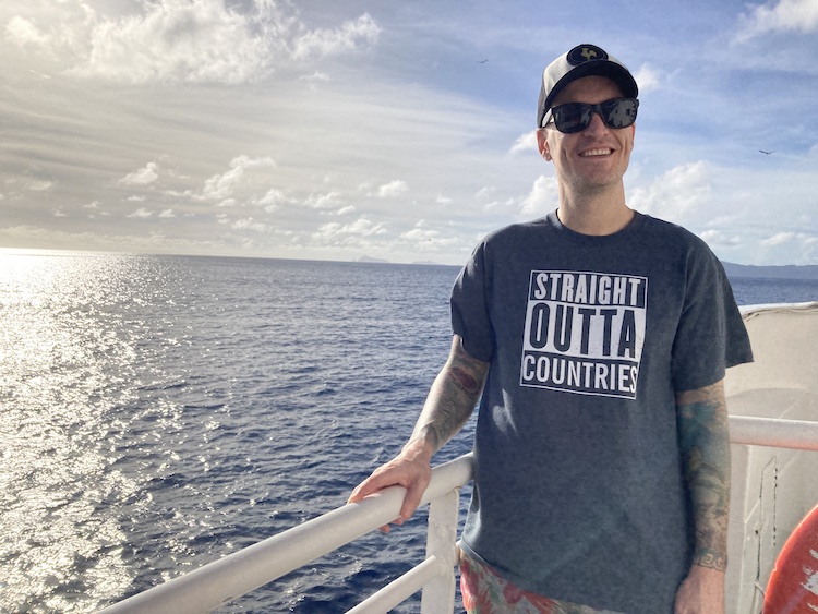 a man standing by a railing on a ferry crossing between islands