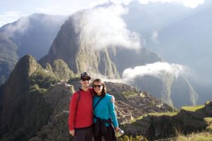 A couple poses together on a hill overlooking Machu Picchu in Peru