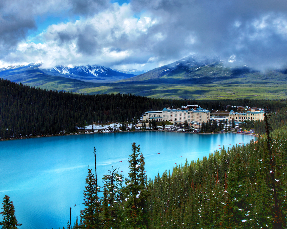 Fairmont Banff Springs seen next to a lake and surrounded by mountains