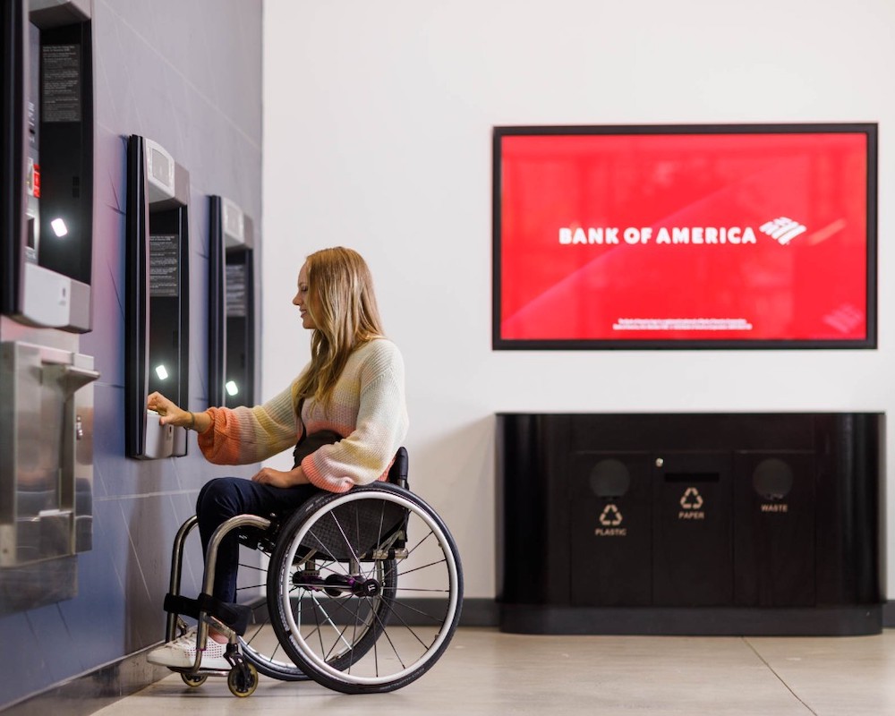 A woman in a wheelchair uses a Bank of America ATM
