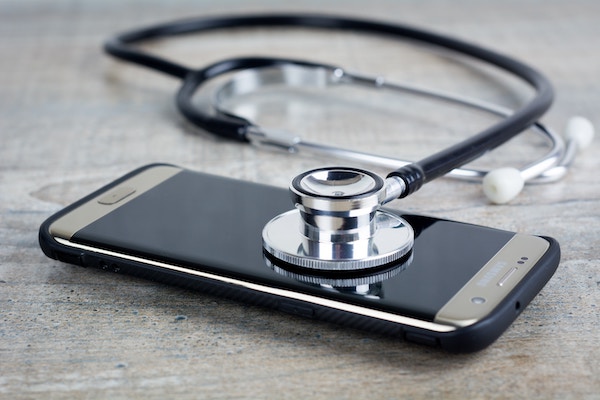 A stethoscope lays on top of a cell phone. Cell phone coverage as a credit card benefit might get you a new phone if yours is damaged.