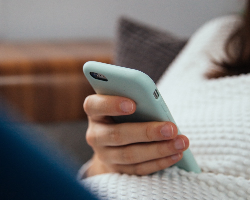 close-up of a hand holding a smart phone resting on a person's lap