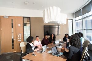 six people sitting around a conference table with computers