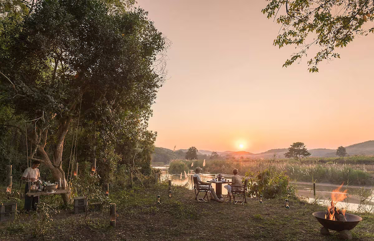 A screenshot of a couple enjoying the sunset at the Four Seasons Tented Camp Golden Triangle in Thailand.