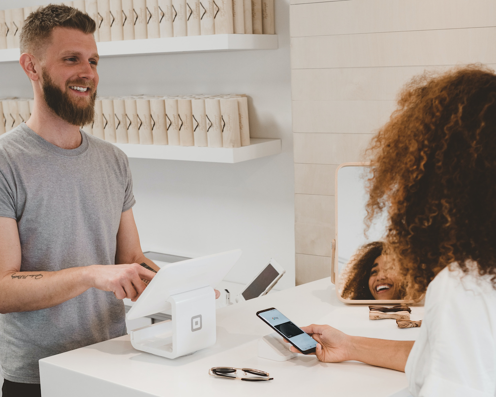 a woman pays by mobile wallet at a small store