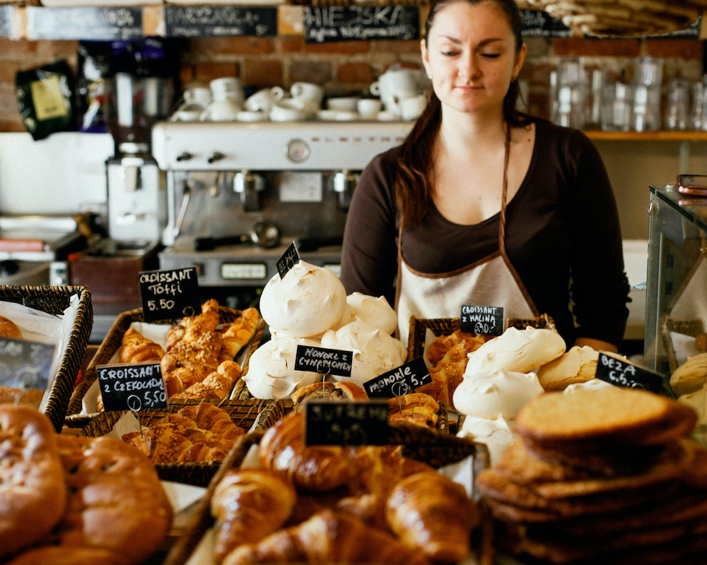 a bakery owner stands behind the counter full of items to buy
