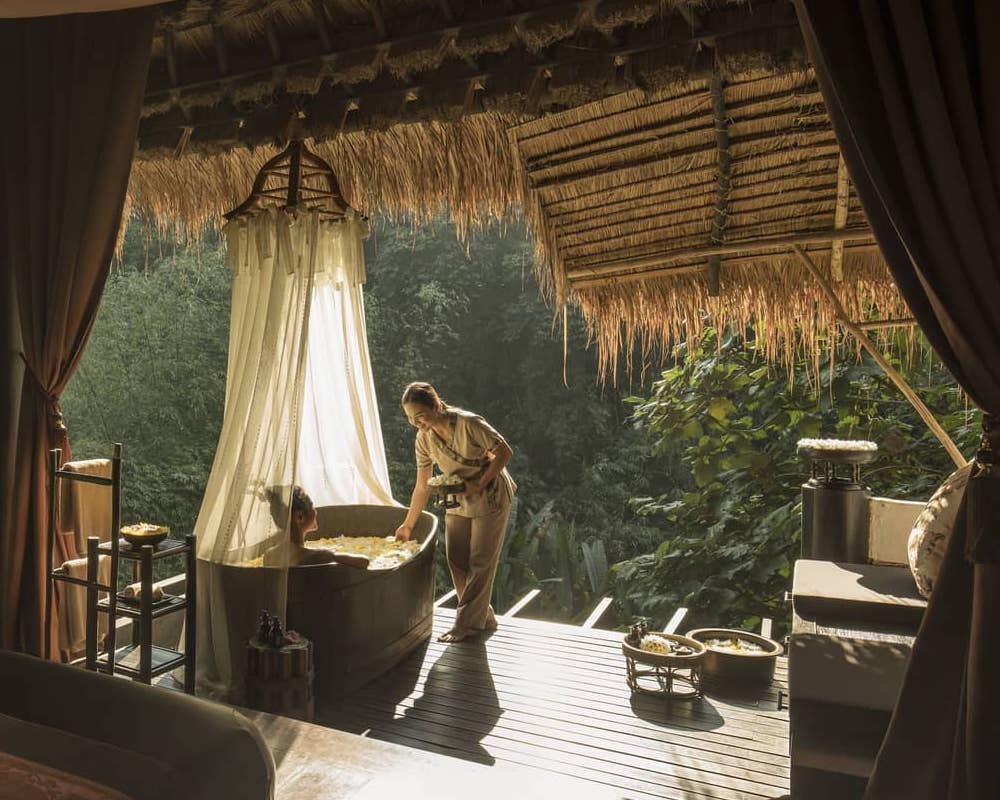 A woman takes a bath overlooking the wilderness at Four Seasons Tented Camp Thailand.