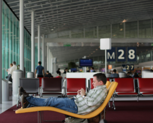 a man lounges in a recliner chair while waiting in an airport