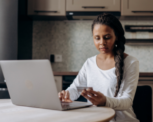 woman with credit card and laptop sitting at a table