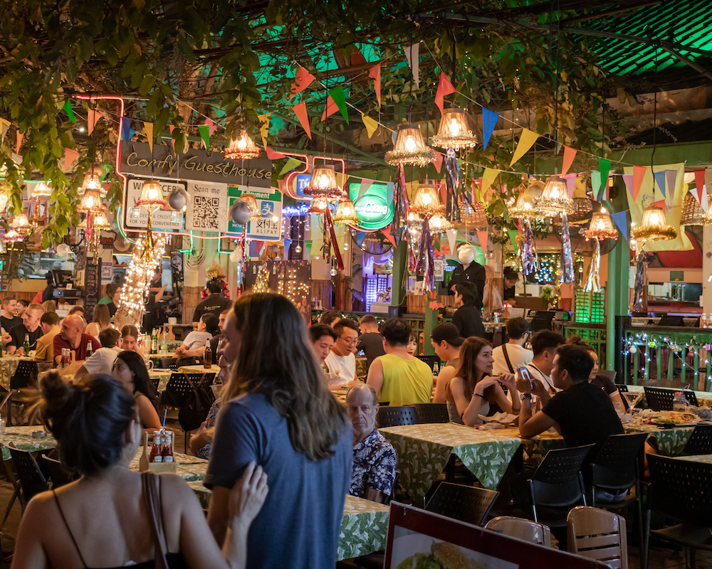 a couple entering a busy outdoor seating area at a restaurant