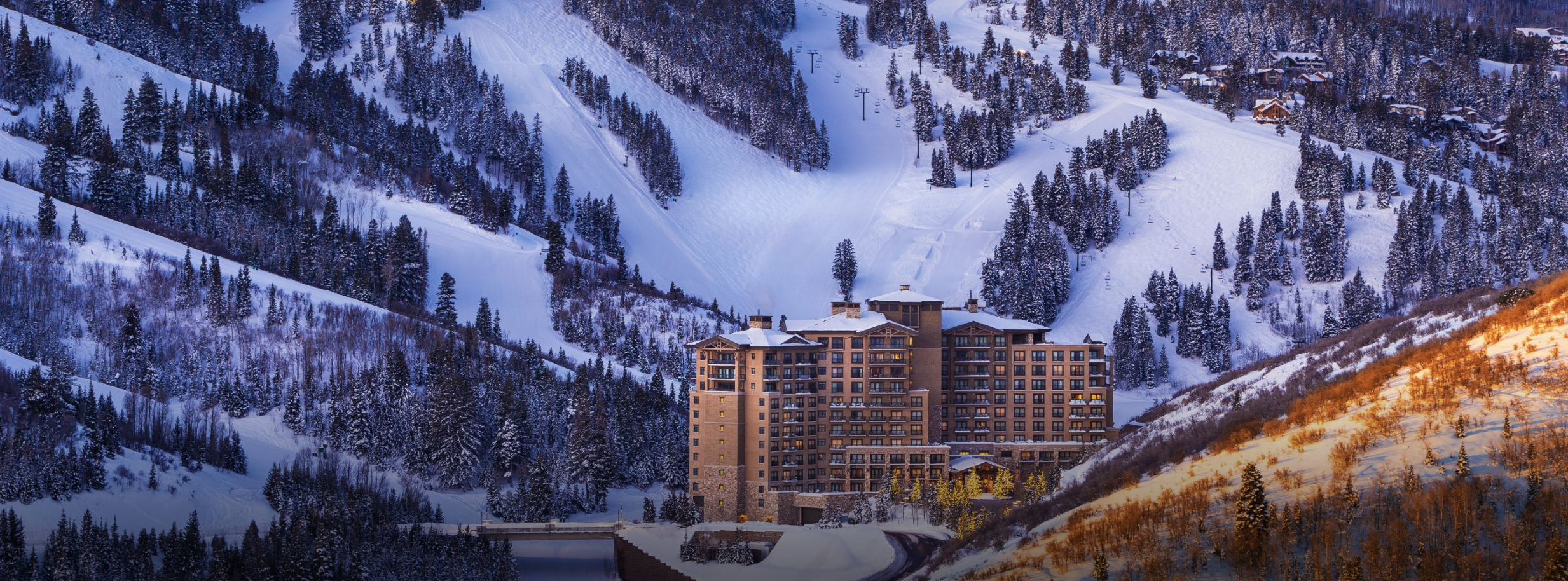 The St. Regis Deer Valley surrounded by a snowy mountain and ski lifts.
