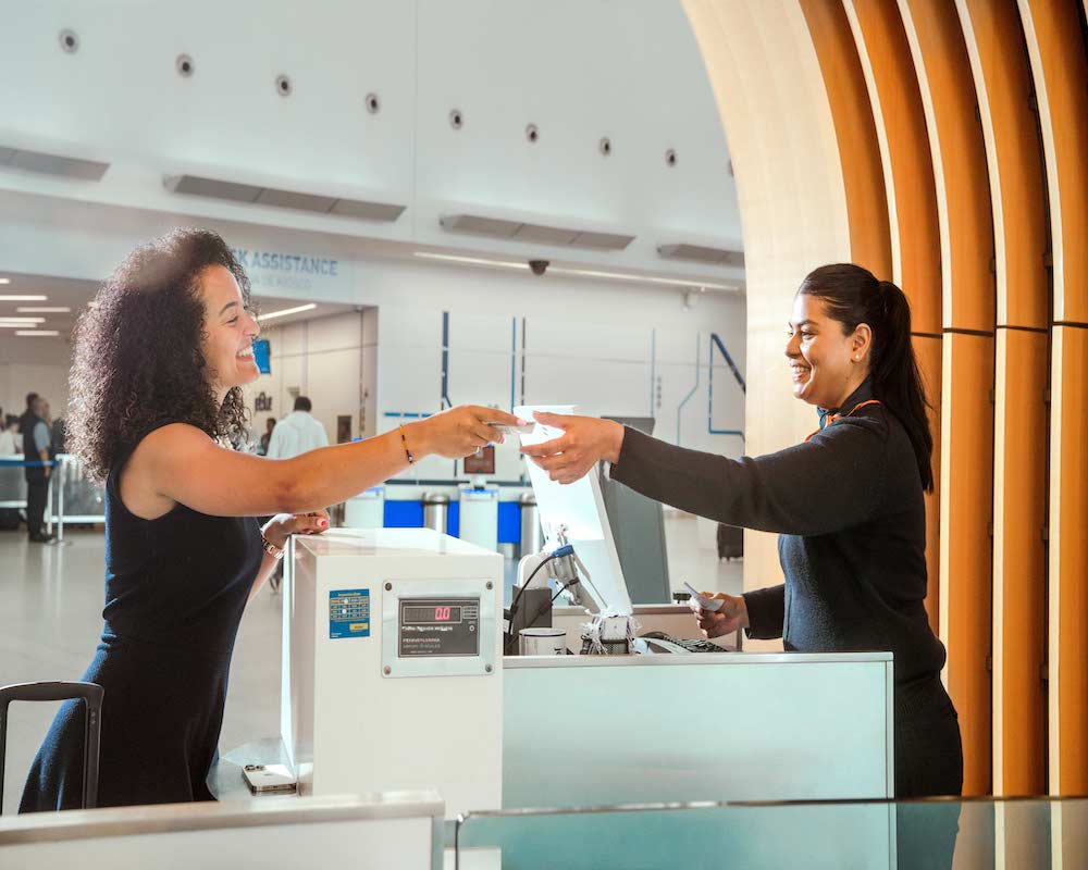 a JetBlue employee helps a customer at the check-in counter