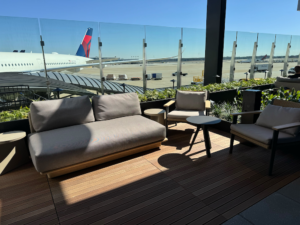 Seats and sofas near a glass wall on the outdoor terrace with planes beyond