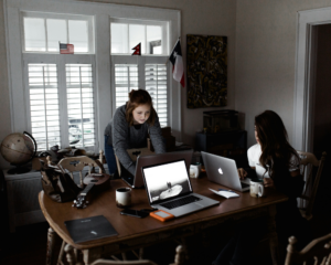 2 women using laptops at a dining room table