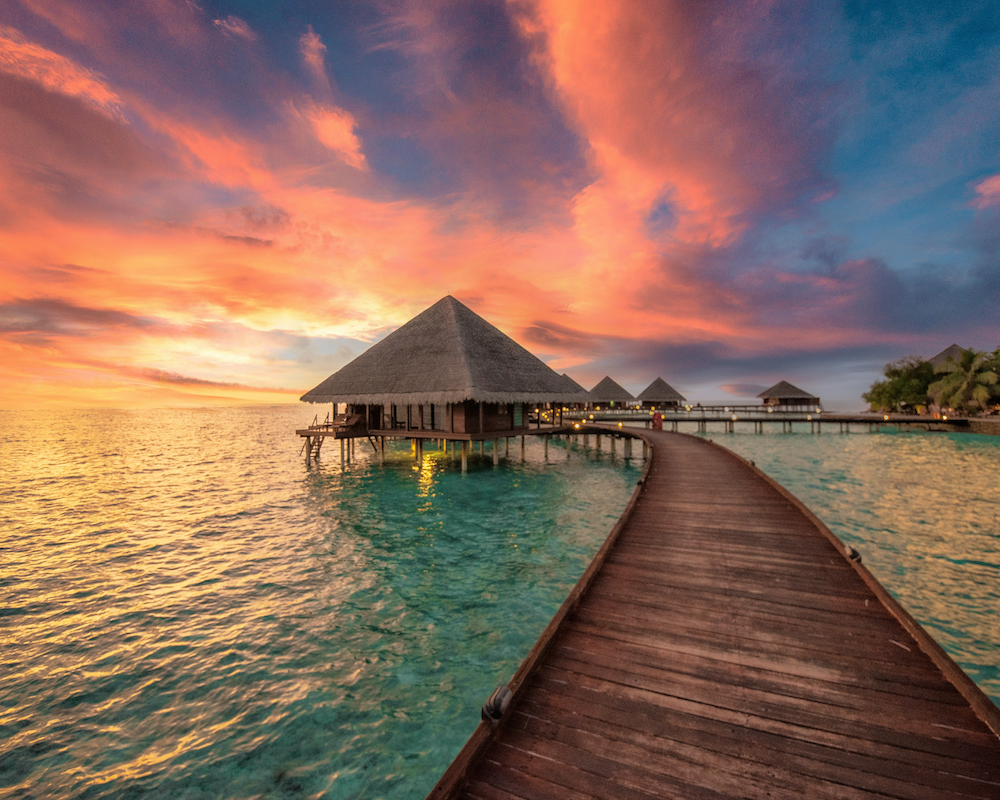 overwater bungalows at a luxury hotel seen at sunset