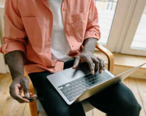 close up of hands, with one hand holding a credit card and the other typing on a laptop