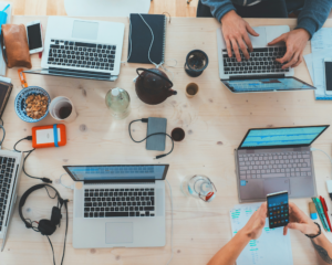 overhead view of multiple laptops and electronic devices on a table