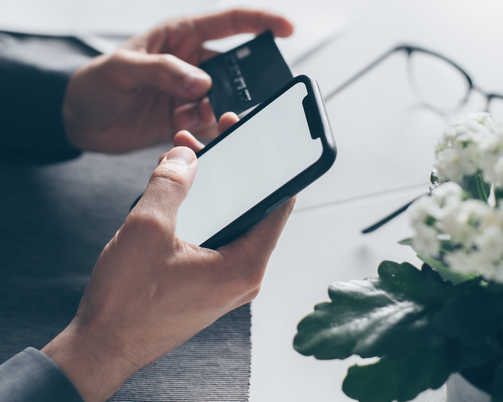 close-up of 2 hands holding a smart phone and credit card
