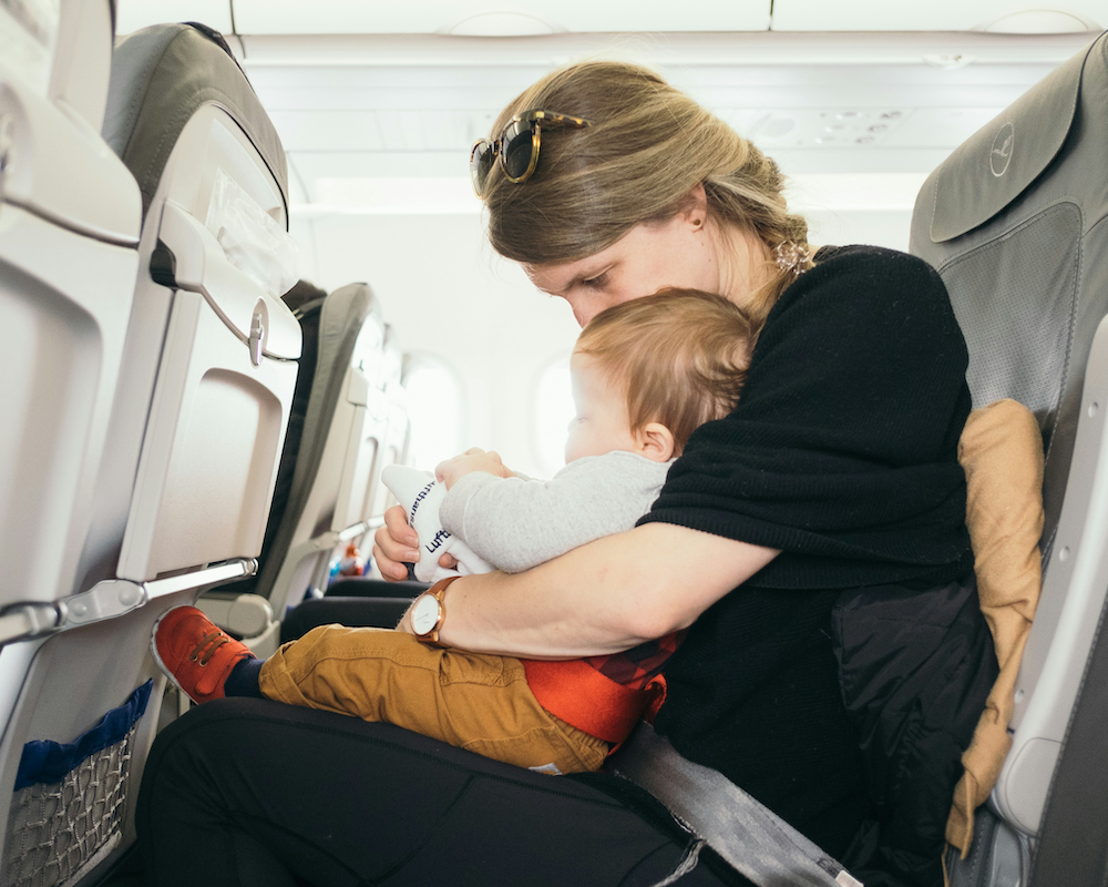 a mother holds an infant on her lap during a flight