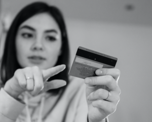 a girl points at a credit card in her other hand