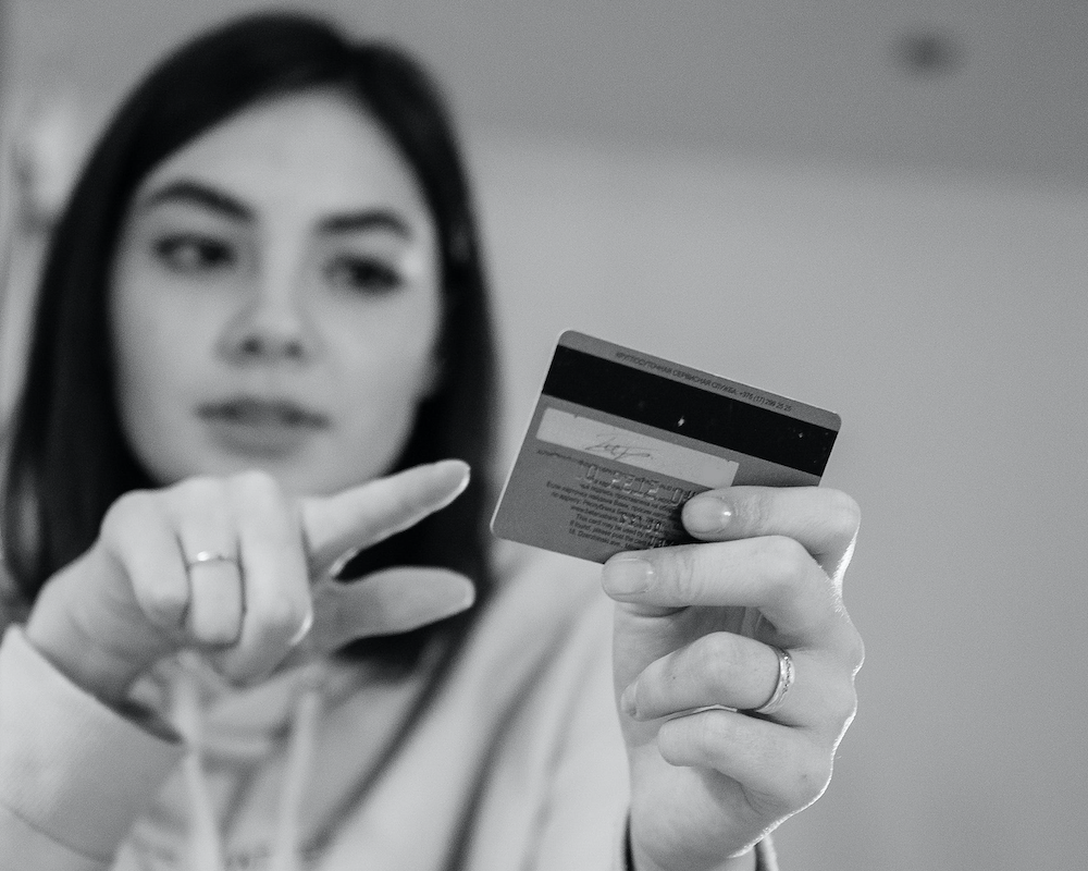 a girl points at a credit card in her other hand