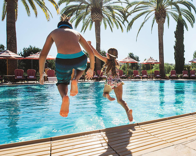 kids jumping into the pool at The Fairmont Grand Del Mar in San Diego