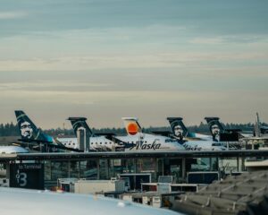 view of Alaska Airlines tail fins on planes parked at gates