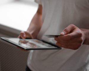 close-up of a hand holding a credit card and another hand holding a tablet