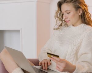 a woman looks at information on her laptop while holding a credit card