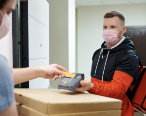 a courier delivers pizzas as an unseen person taps a credit card to pay for them