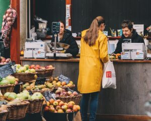 a woman pays for produce at a small outdoor market