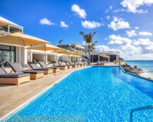 lounge chairs near a pool with a beach beyond