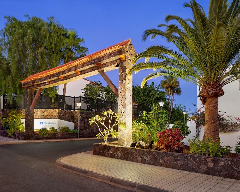 a palm tree-flanked arch with a Wyndham sign leading to a hotel entrance
