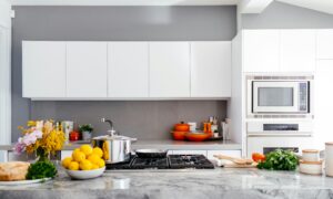modern kitchen showing white cabinets an island fruit pots and pans and a microwave