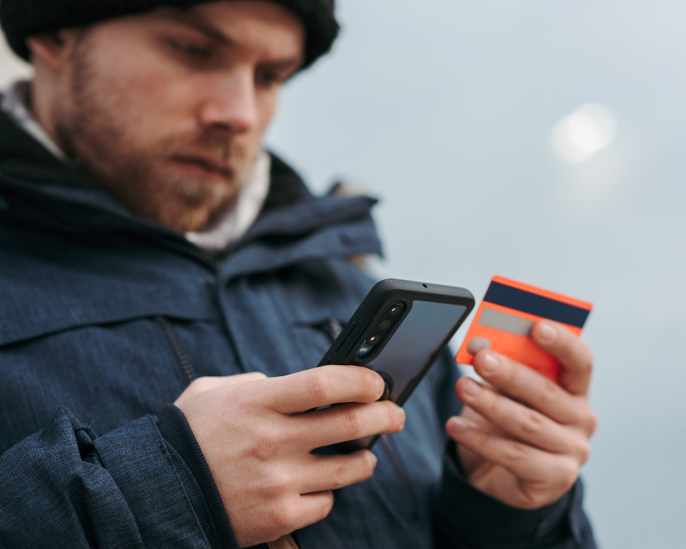 close-up of a man looking at a credit card while reading something on a smart phone
