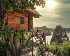a couple rests on the steps to a tree house while overlooking a bay
