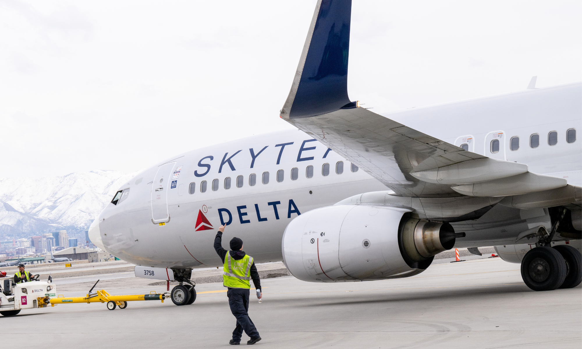 A Delta Air Lines Boeing 737 in SkyTeam livery taxing with a ramp agent in the center of the image.